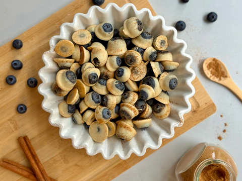 Frische Blaubeeren, halb mit weißer Chai-Schokolade überzogen und mit etwas Zimt bestreut in einer Schale.