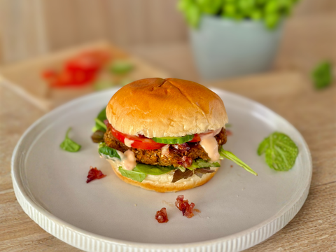 Vegetarischer Burger mit knusprigem Grünkern-Patty aus dem Airfryer, Salat, Tomaten, Gurken und karamellisierten Zwiebeln im Brioche-Bun.